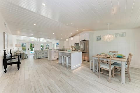 Your spacious open-concept retreat flows seamlessly from kitchen to dining, where coastal charm meets modern comfort under beautiful white-washed ceilings.