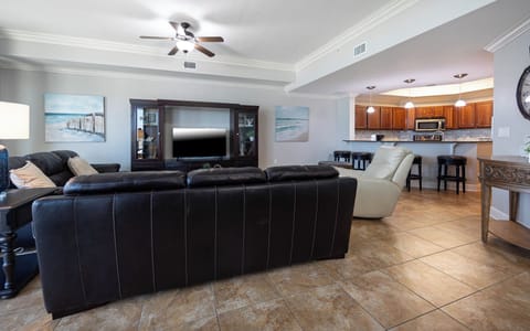 The cozy living space features a large TV, comfortable seating, and a view of the stylish kitchen with rich wood cabinetry