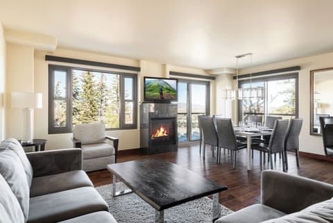 Bright open living room with large windows, dark hardwood floors, and gas fireplace under the flat screen TV