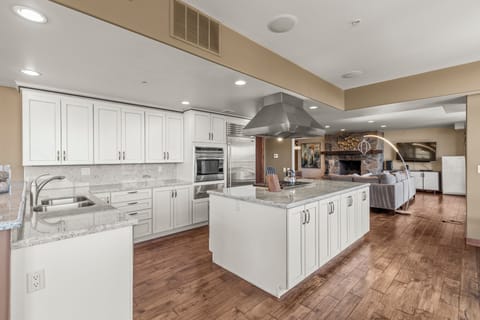 The spacious kitchen has many white cabinets, a wrap around counter and breakfast bar, and freestanding island.