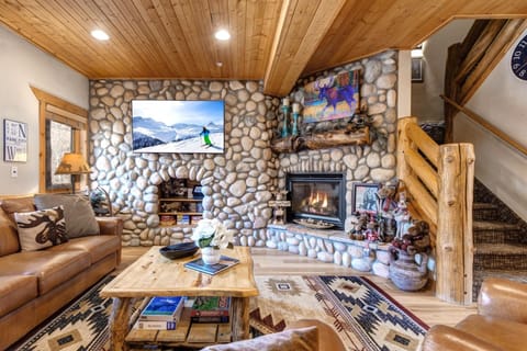 Gather in your lodge-style living room with vaulted ceilings, a large Smart TV, and a cozy stone fireplace.