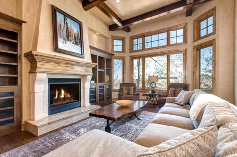 Gather in the main living room with vaulted ceilings, fireplace, and picture windows framing the mountain view.