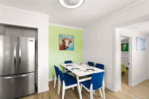 Siesta Key beach retreat dining area with six seats, ocean-blue chairs, and playful artwork—crafted for breezy dining and laid-back coastal living.