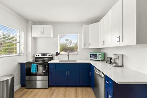 Siesta Key Beach kitchen with white counters, blue cabinetry, and natural light