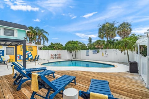 Siesta Key Beach backyard pool with a vibrant mural, shaded pergola seating, and palm-fringed privacy—perfect for relaxed, flip-flop-ready lounging.
