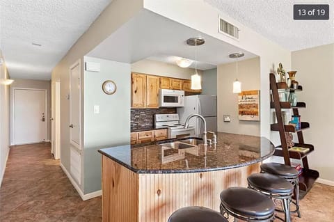 Counter has under cabinet lighting. Custom cabinets and glass tiled back splash.