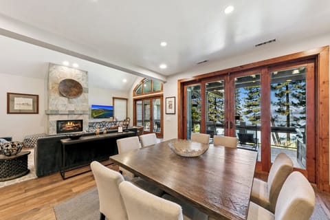 Gather around your elegant dining table while the fireplace crackles nearby and natural light streams through stunning wood-framed windows.