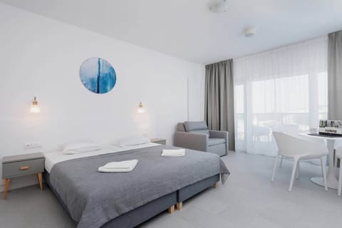 A bright and modern room with a double bed, small bedside tables, and a seating area with a coffee table and armchairs.