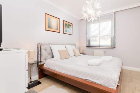 The main bedroom with a double bed, stylish bedding, and artwork on the walls. A bright and airy feel is created by the natural light from the windows.