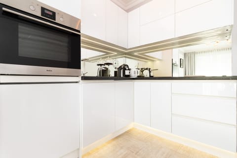 A close-up of the modern kitchen, featuring sleek white cabinets, an oven, and bright under-cabinet lighting.