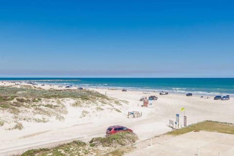 Pristine coastal beach with clear blue waters and sandy shoreline featuring vehicle access and lifeguard stations.