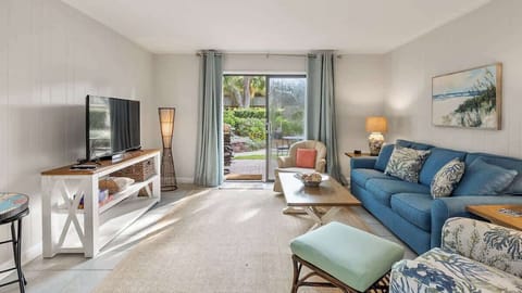 Bright living room with a blue sofa and garden access through sliding glass doors