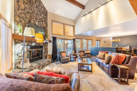 Unwind in your spacious living room featuring a stunning stone fireplace, vaulted ceilings, and cozy leather seating perfect for mountain evenings.