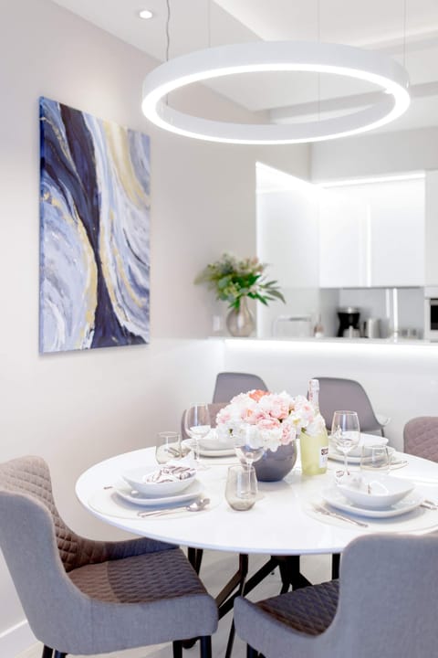 A dining table and chairs set in a contemporary living space with neutral decor and modern lighting.