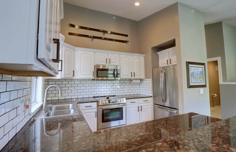 Modern kitchen with white cabinets, stainless steel appliances, granite countertops, and subway tile backsplash. Skis mounted on the wall as decor.