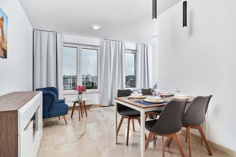 A modern living room with a comfortable blue sofa, a coffee table, and a TV mounted on the wall.
