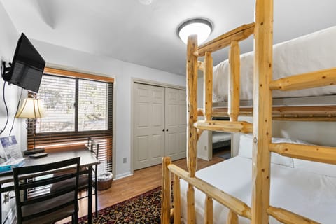 Your cozy room features sturdy wooden bunk beds with fresh linens, a work desk, and entertainment setup for comfortable group stays.