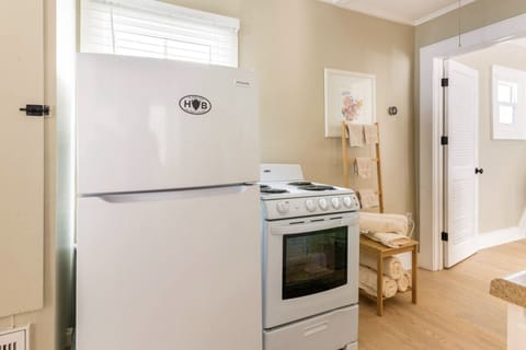 Full Fridge and oven in kitchen area Towel rack showing across from shower