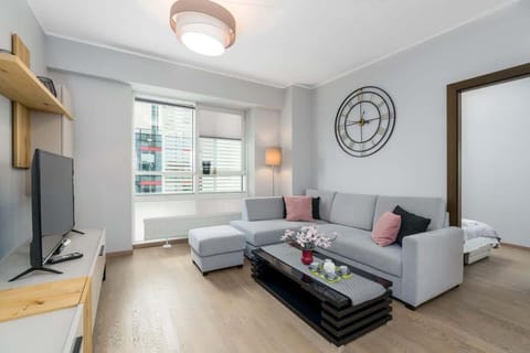 A bright and cozy living room with a large gray sectional sofa, a coffee table, and wooden floors.