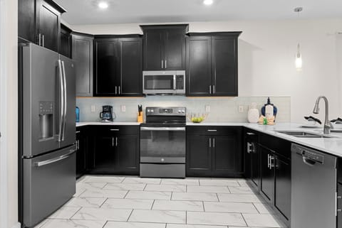 Cook your favorite meals in this sleek modern kitchen with stainless steel appliances and elegant dark cabinetry.