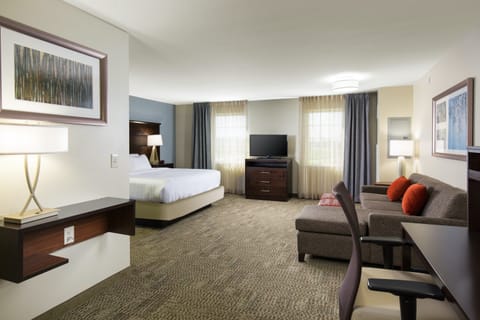King bed in the open studio layout — flatscreen TV faces the bed with a pull-out sofa just steps away