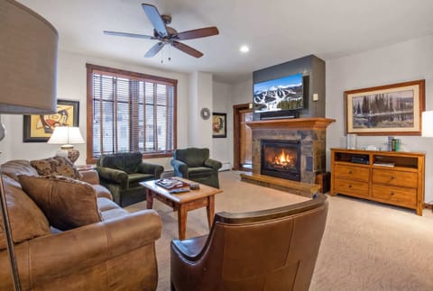 Living room with gas fireplace, mounted TV, and access to private balcony