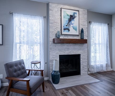 Gather with your loved ones in the inviting living room, centered around a modern stone fireplace.