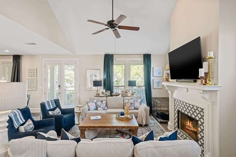 - Cozy up around the fireplace in this welcoming living space with French door access to the outdoors - Neutral tones & layered pillows create a coastal vibe perfect for relaxing - Let the natural light pour in through windows framed by navy drapes