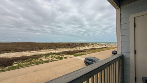 Expansive coastal view showcasing pristine beachfront with rolling dunes, clear blue skies, and convenient parking access to the sandy shores.