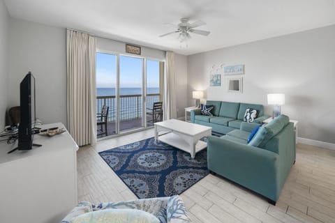 Your oceanfront living room invites you to unwind on plush teal sofas while enjoying panoramic sea views through floor-to-ceiling windows.