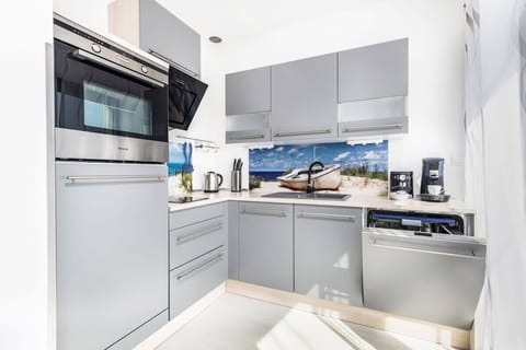 A modern kitchen with stainless steel appliances, white cabinets, and a clean countertop.