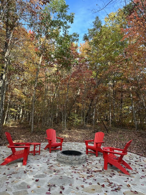 Stone patio set back in the woods with fire pit.
