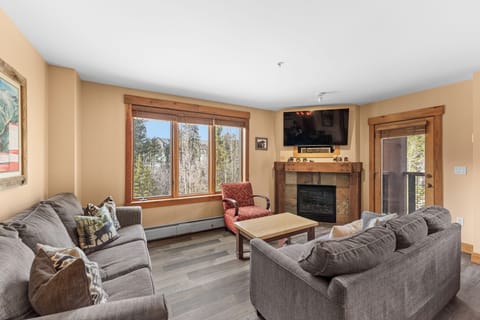 Unwind in your cozy living room where plush gray sofas surround a warm fireplace, perfect for mountain evenings together.