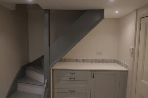 Kitchen with fridge and freezer box, narrow stairs to floor above