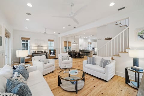 Sink into plush white sofas in your bright, airy living space featuring soaring ceilings and warm wood floors.