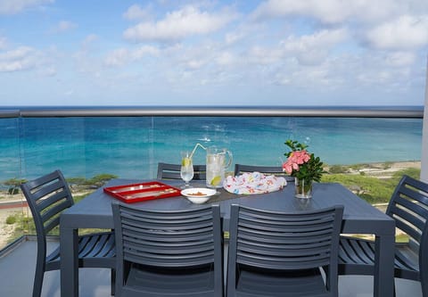 Stunning beachfront dining terrace overlooking crystal-clear turquoise waters, with refreshing drinks and flowers set to welcome guests to a memorable meal.
