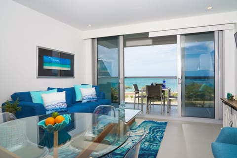 Sink into the plush blue sofa and gaze out to your private balcony with stunning turquoise sea views. Bright, airy, and perfectly styled for your coastal escape.