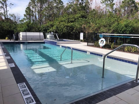 Experience relaxation in our stunning pool area, where sleek blue tiles and inviting steps lead to crystal-clear water, all surrounded by lush greenery for a refreshing escape just steps away from your door.