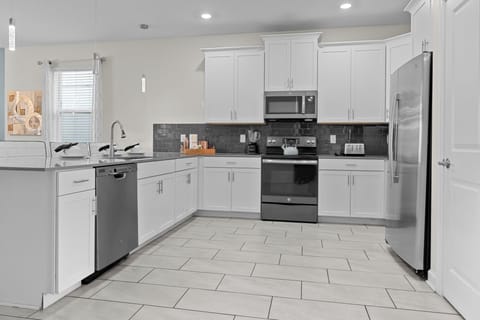 Your fully equipped kitchen features crisp white cabinetry, sleek stainless appliances, and a stylish subway tile backsplash—perfect for creating memorable meals together.