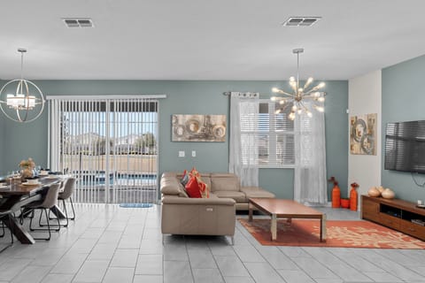 Relax in your spacious open-concept living area with modern furnishings, stylish decor, and peaceful pool views through sliding glass doors.