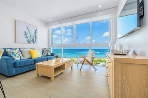 Wake up to turquoise waters outside your floor-to-ceiling windows, where modern comfort meets oceanfront luxury in this bright, coastal-inspired living space.