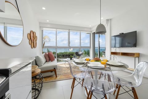 Picture yourself relaxing in this bright, airy space where modern style meets coastal comfort. Floor-to-ceiling windows frame breathtaking ocean views as sunlight fills the dining and lounge area—your perfect retreat.