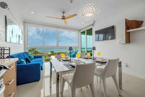 Modern living and dining space with floor-to-ceiling windows framing stunning ocean views. Relax on plush seating or enjoy meals at your dining table while the sea breeze flows through.