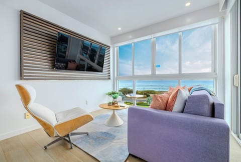 Unwind in your bright, modern living room with floor-to-ceiling windows framing stunning ocean views. The sleek design and comfortable seating invite you to relax and soak in the coastal beauty.