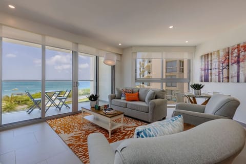 Sink into plush seating and take in stunning ocean views through floor-to-ceiling windows, where your beachfront retreat awaits with coastal breezes and modern comfort.