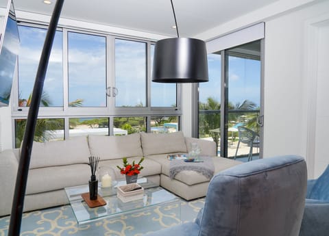 Unwind in your bright living space with plush seating and floor-to-ceiling windows framing tropical views and the sparkling pool just steps from your door.