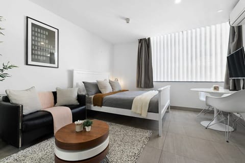 A studio with a queen-sized bed and a 2-seater sofa.