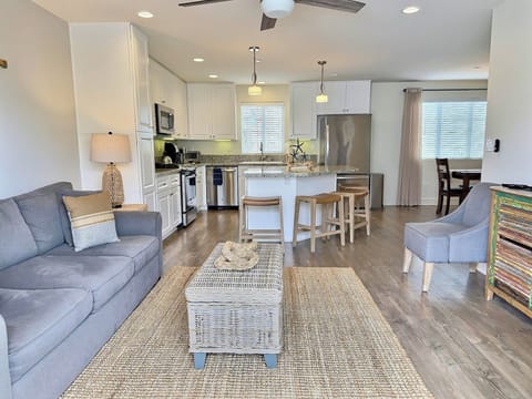 Here’s another view of the spacious open living area, featuring a large gathering room with a queen sleeper sofa, SmartTV, island bar with seating, a family dining area, and a chef-grade kitchen — all designed for comfort, style, and easy coastal living.