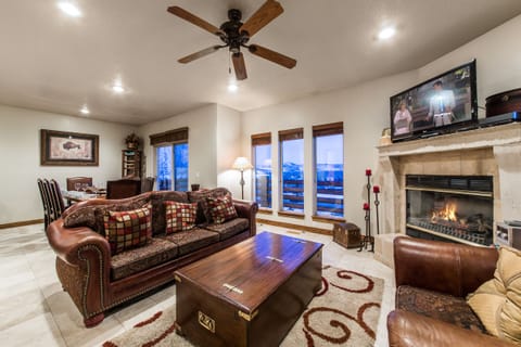 Unwind in the cozy living room featuring a beautiful fireplace, warm ambient lighting, and plush seating perfect for relaxing after a day of adventure. Enjoy your favorite shows on the flat-screen TV in a welcoming, mountain-style atmosphere.
