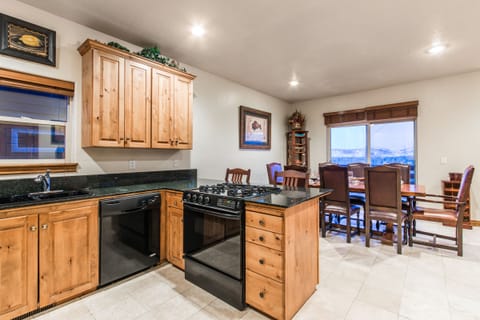 This fully equipped kitchen features warm wood cabinetry, modern black appliances, and a spacious countertop perfect for preparing meals. Whether you're cooking breakfast or hosting a dinner, this inviting space has everything you need.